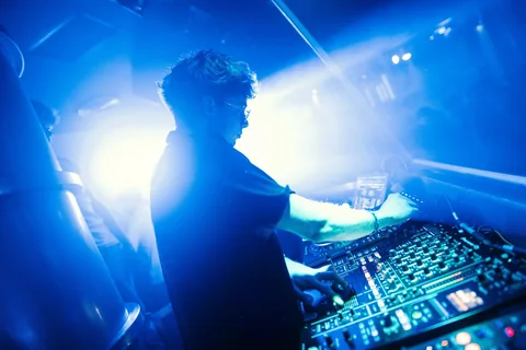 DJ Sputnik alla console durante un live set illuminato di blu