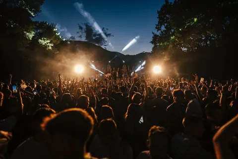 Il pubblico all'aperto tra luci e fasci luminosi durante il live